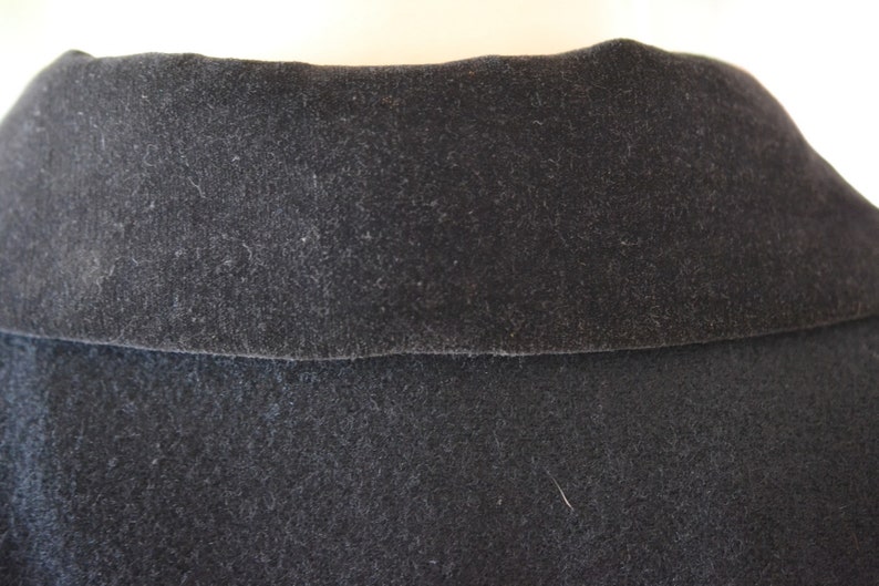 May include: Close-up of a black velvet collar on a garment. The collar is soft and plush, with a subtle sheen.