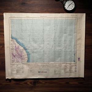 Puede incluir: Mapa antiguo de Trengganu, con detalles costeros en tonos morados y azules. El mapa incluye líneas de cuadrícula y texto, con una escala en metros y pies. El mapa está envejecido, con un aspecto desgastado, y descansa sobre una superficie de madera oscura.
