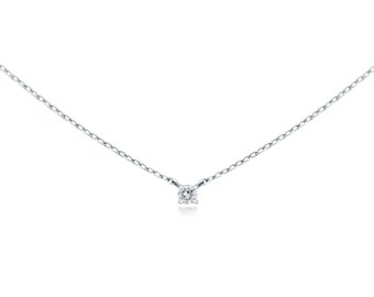 May include: A delicate silver necklace featuring a small, round, clear gemstone pendant. The chain is thin and appears to be made of silver. The pendant is centered on the chain, creating a minimalist and elegant design.