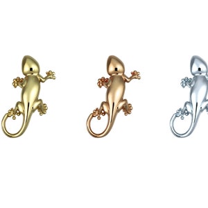 May include: Three metal lizard figurines in gold, rose gold, and silver. Each lizard has a detailed body and curled tail, perfect for jewelry or decorative accents. The lizards are displayed against a white background.
