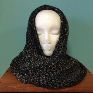 May include: A black and white infinity scarf made of chunky yarn. The scarf is draped over a white mannequin head.
