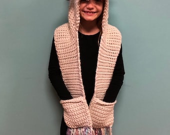 May include: A white crocheted unicorn hooded scarf with a pink, blue, and white yarn mane and horn. The scarf has pockets and a fringe.