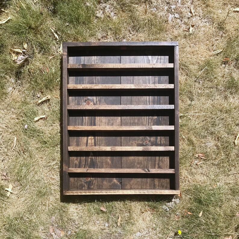 May include: A dark brown wooden shelf unit with six shelves. The shelves are stained a dark brown color and have a rustic look.