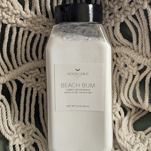 May include: White plastic jar with a black lid and a white label that says "MOON CHILD" and "BEACH BUM CARPET DEODORIZER MADE IN MT. SAVAGE MD NET WT 16 OZ (453 G)".