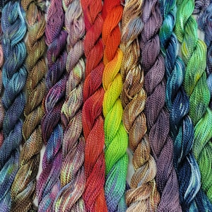 May include: A collection of colorful embroidery floss in a variety of hues, including red, orange, yellow, green, blue, and purple. The floss is twisted into individual bundles, showcasing the vibrant color variations. Ideal for craft projects.