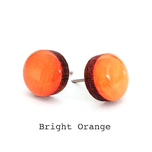 May include: A pair of bright orange wooden stud earrings. The earrings are made of wood with a bright orange resin inlay.