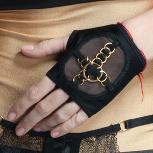 May include: Black fingerless gloves with a mesh panel and gold chain detail.