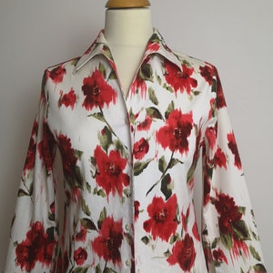 May include: A white button-up shirt with a red floral print. The shirt has a collared neckline and long sleeves.