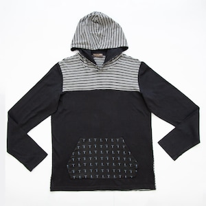 Può includere: Felpa con cappuccio nera a maniche lunghe con cappuccio e pannello pettorale a righe. La felpa con cappuccio presenta una tasca a marsupio con un motivo ripetuto. Il cappuccio e il pannello pettorale hanno un design a righe bianche e nere.