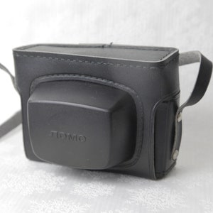 May include: Black leather camera case with a strap and the word "LOMO" embossed on the front.