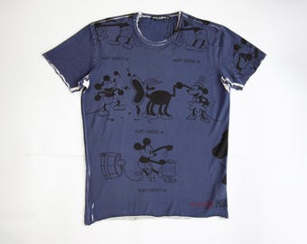 May include: A navy blue t-shirt featuring a distressed design with cartoon characters. The shirt has a crew neck and short sleeves. Black cartoon figures are printed across the front. The text "MJP159001.ai" is printed on the shirt.