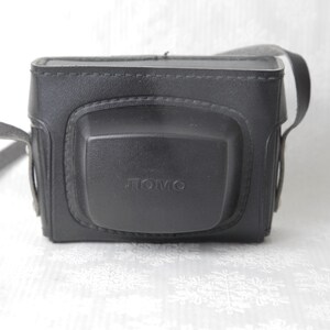 May include: Black leather camera case with a strap and the word "TOMO" embossed on the front.