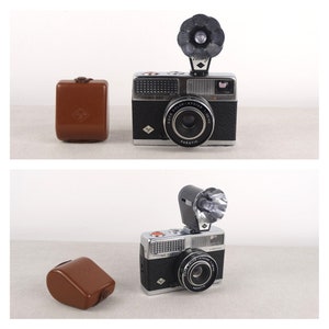 May include: Two black and silver 35mm film cameras with built-in flash units and leather cases. The cameras have a silver lens with a black ring around it. The text "Agfa Color-Apotar 1:2.8/35" is printed on the lens. The text "Agfa Optima 300" is printed on the top of the camera.