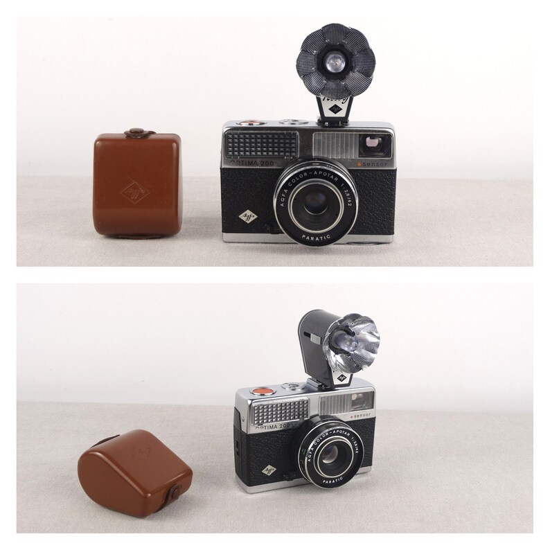 May include: Two black and silver 35mm film cameras with built-in flash units and leather cases. The cameras have a silver lens with a black ring around it. The text "Agfa Color-Apotar 1:2.8/35" is printed on the lens. The text "Agfa Optima 300" is printed on the top of the camera.