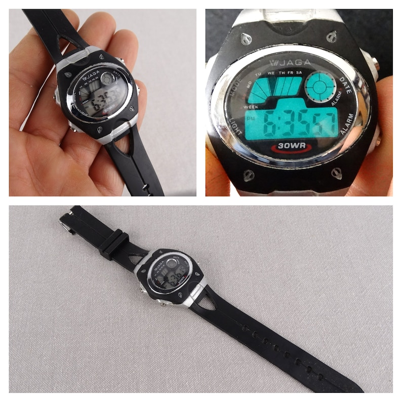 May include: Black digital wristwatch with a silver face and black band. The watch face displays the time, date, and day of the week. The watch is water resistant to 30 meters.