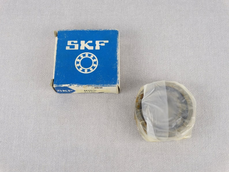 May include: A blue box with the word "SKF" printed on it. The box contains a new SKF bearing. The bearing is in a clear plastic bag.