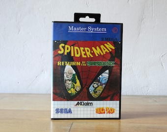 May include: A Sega Master System game cartridge for Spider-Man: Return of the Sinister Six. The cartridge is black with a blue and red label featuring a close-up of Spider-Man's face and the game title. The label also includes the text "2 MEGA" and "Aklaim".