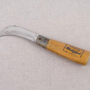May include: A curved, silver-coloured knife with a wooden handle. The handle is marked with the text "19415" and a small image of a fish.