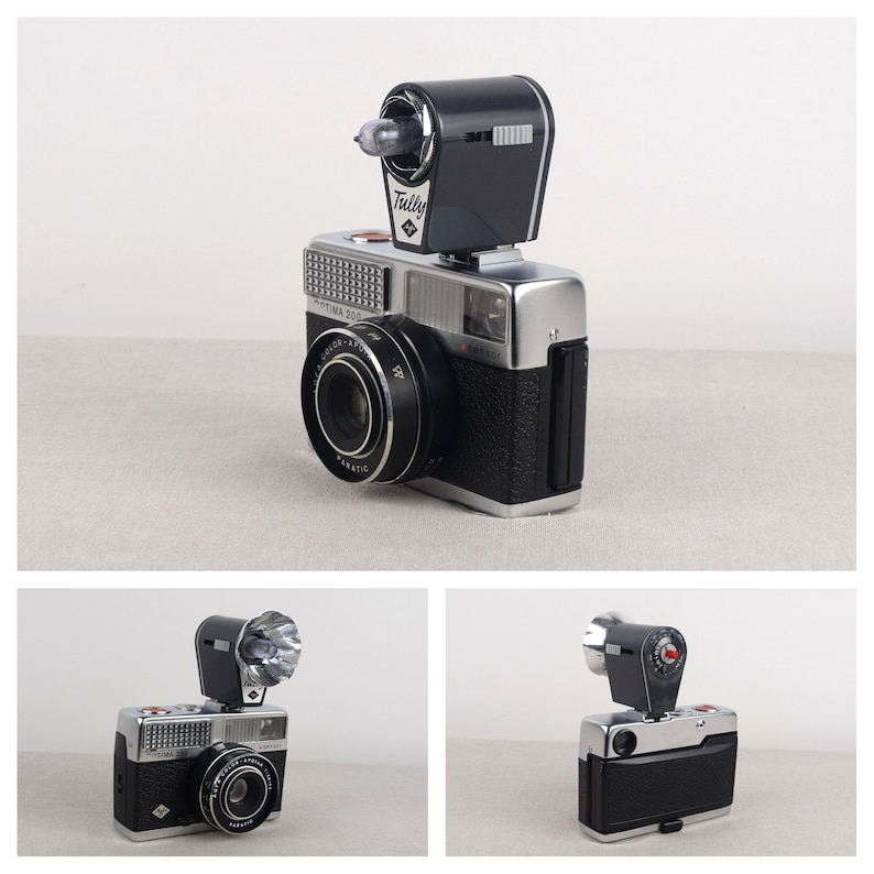 May include: A silver and black 35mm film camera with a flash attachment. The camera has a lens with a black ring around it and the text "OPTIMA 503" on the front. The flash attachment is black and has the text "Tully" on it.