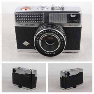 May include: A black and silver Agfa Optima 200 35mm film camera with a silver lens and a black leatherette body. The camera has a built-in flash and a viewfinder on the top. The lens is labeled "Agfa Color-Apotar 1:2.8/42 Paratic".