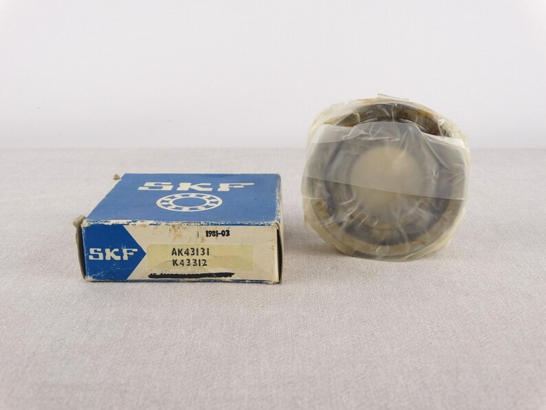 May include: A blue and white box with the text "SKF" and "AK43131 K43312" on it. The box contains a round, silver bearing with a clear plastic cover.
