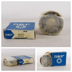 May include: A close-up of a sealed package containing an SKF bearing. The package is blue and white with the SKF logo and the bearing number AK43131 K43312. The bearing is wrapped in clear plastic.