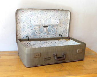 May include: A vintage brown suitcase with a floral patterned lining. The suitcase has a brown leather handle and two metal clasps.