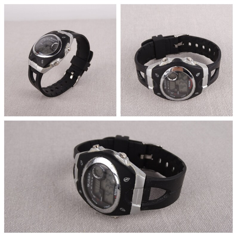May include: A black digital wristwatch with a silver face and black rubber band. The watch has a digital display and a round analog face.