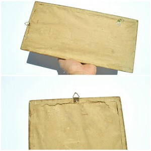 May include: The back of a brown picture frame with a metal hanging hook. The frame is made of wood and has a simple design.