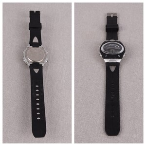 May include: A black digital wristwatch with a silver case and black rubber band. The watch has a digital display with multiple time zones and a stopwatch function.