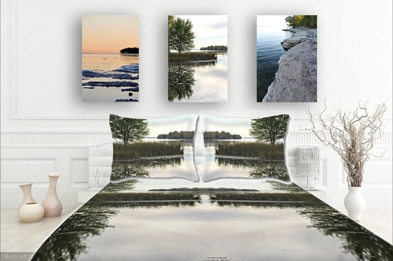 May include: A bedroom with a white bedspread and two pillows featuring a lake scene with a tree reflected in the water. Three framed pictures of a lake scene with a tree and a rocky shoreline are hanging on the wall behind the bed.