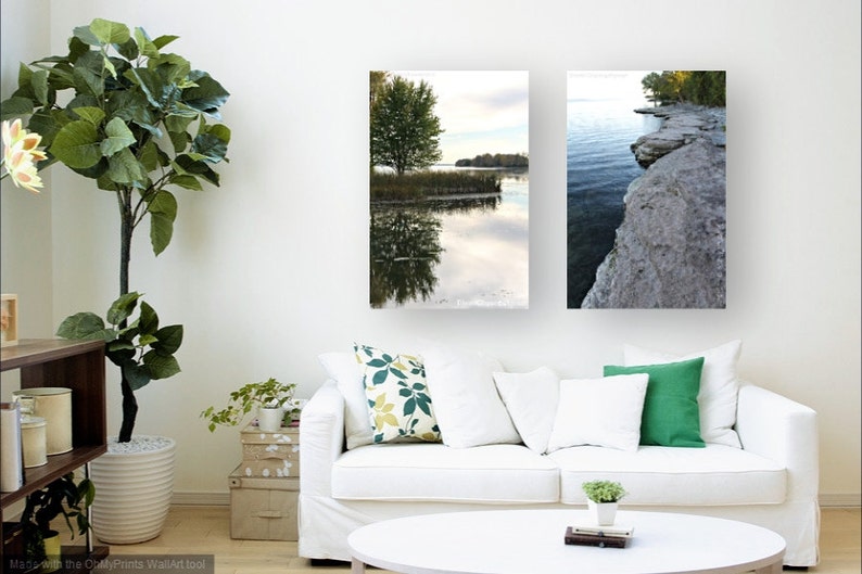 May include: Two framed landscape photographs of a lake with a tree and a rocky shoreline. The photographs are hung on a white wall above a white couch.