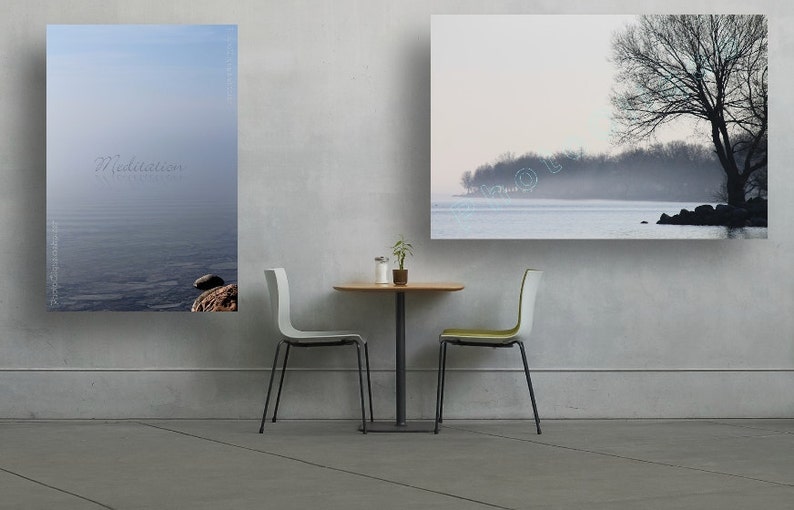May include: Two framed landscape photographs of a lake with a tree in the foreground and a misty background. The photographs are hanging on a white wall above a small table with two chairs.