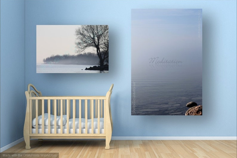 May include: Two framed photographs of a misty lake scene with a tree in the foreground. The top photo has the word "Meditation" written in cursive on the water. The bottom photo shows a tree line in the distance. Both photos are hanging on a light blue wall with a white crib in the foreground.
