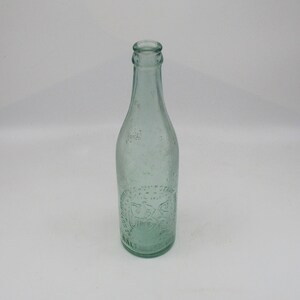 May include: A clear glass bottle with a textured surface. The bottle has a label with the text "SALT LAKE BEER" embossed on it.