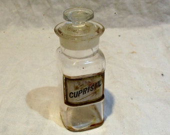 May include: A clear glass bottle with a glass stopper and a label that reads "CUPRISUL".