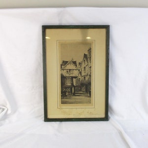 May include: A black and white framed print of a street scene with old buildings. The print is in a green frame.