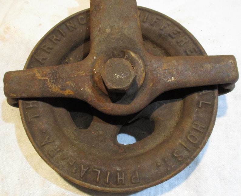 May include: A rusty cast iron pulley with a handle. The pulley is labeled "PHILADELPHIA HOIST" and "HARRING DIFFERENTIAL".
