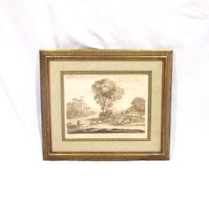 May include: A framed sepia-toned landscape print. The artwork depicts a rural scene with trees, figures, and a building. The frame is gold-colored with a textured border, adding a classic touch to the artwork.