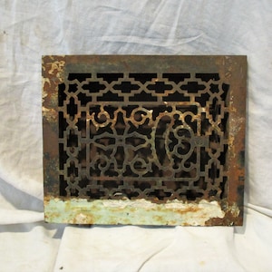 May include: A vintage cast iron floor register with a decorative, intricate design. The register is rusty and has a green patina on the bottom edge.