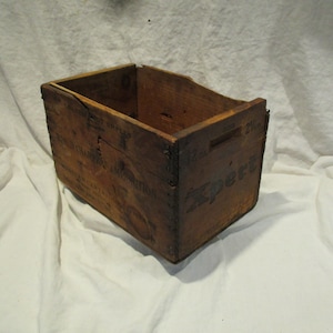 May include: A vintage wooden crate with the text "Expert" printed on the side. The crate is made of brown wood and has a worn, rustic appearance.