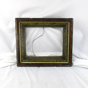 May include: Rectangular picture frame with a dark brown exterior and a decorative olive green and gold interior border. The frame has a distressed appearance and a black wire is visible.