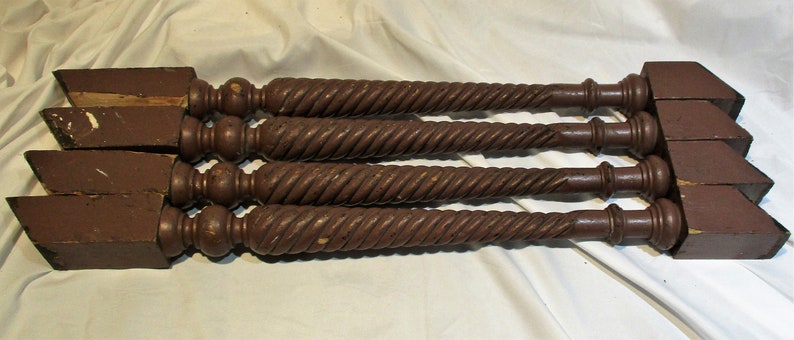 May include: Four dark brown wooden table legs with a twisted design. Each leg has a square base and a rounded top.