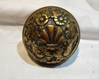 May include: A vintage brass door knob with an ornate design featuring a shell, flowers, and leaves.