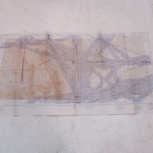 May include: A vintage map with faded blue and red lines on a white background. The map is folded and shows signs of age and wear.
