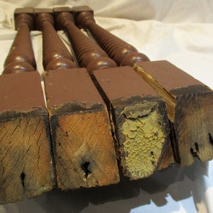 May include: Four antique wooden balusters with a dark brown paint finish. The balusters have a twisted design and are in various states of wear and tear.