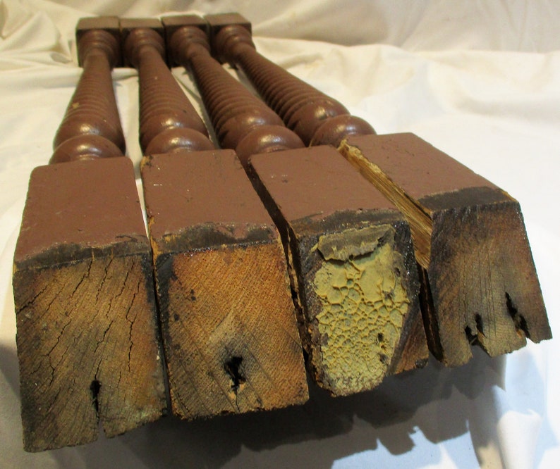 May include: Four antique wooden balusters with a dark brown paint finish. The balusters have a twisted design and are in various states of wear and tear.