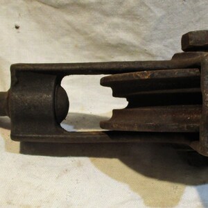 May include: A vintage cast iron pulley with three wheels. The pulley has a hook on one end and a metal loop on the other end.