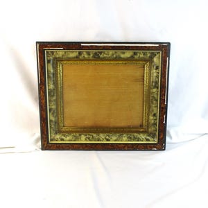 May include: Rectangular picture frame with a wooden back and a decorative border. The frame has a dark brown outer edge, a green and gold middle section, and a gold inner edge. The frame is empty.