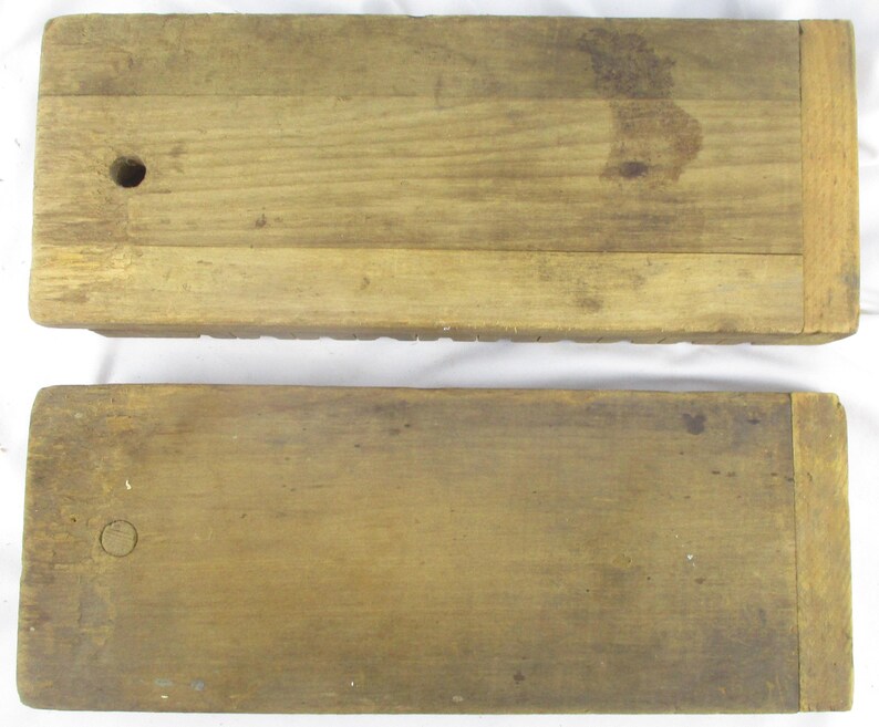 May include: Two rectangular wooden blocks with a natural light brown finish. Each block features a smooth surface with visible wood grain, a small circular hole on one end, and a distinct vertical seam near the opposite edge of the wood.